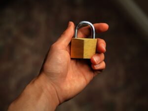 Mano sosteniendo un candado de latón, símbolo de seguridad y protección de datos