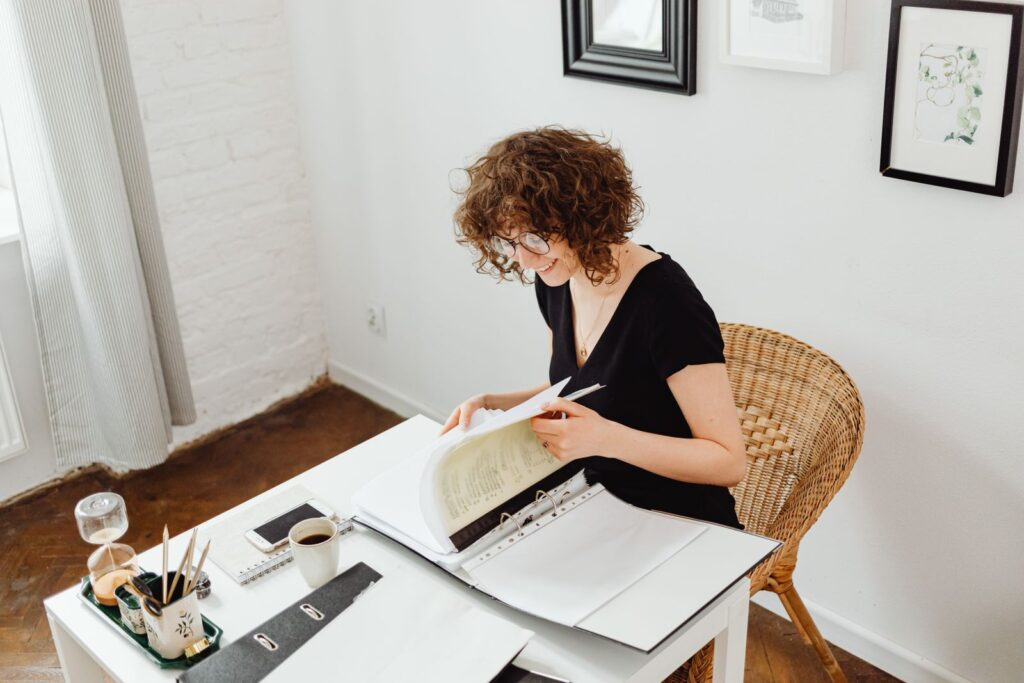 Mujer revisando con una sonrisa los documentos de su situación económica en casa